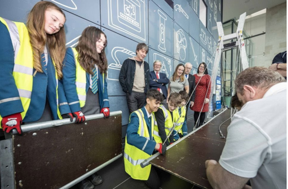 The team from Hood McGowan Kirk Big Bridge Workshop with students and Prof Brian Cox watching